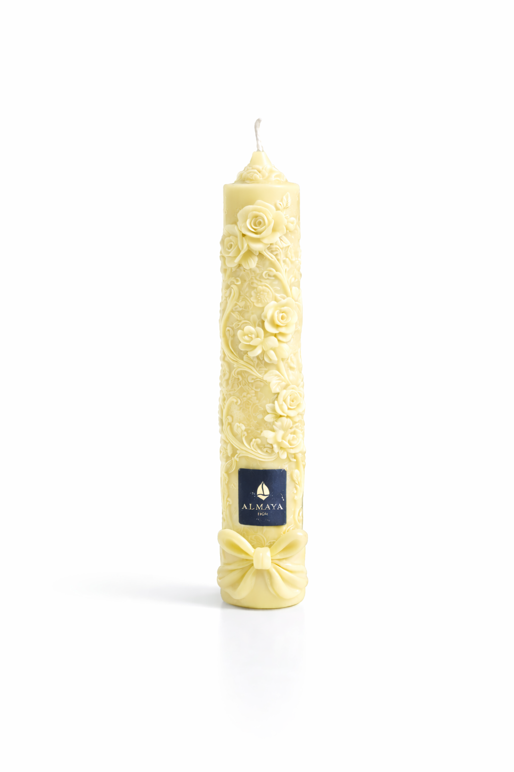 Vela decorativa artesanal color amarillo marfil con relieve floral en 3D, diseño romántico con rosas y lazo en la base, acabados de lujo y etiqueta azul marino, fondo blanco minimalista, vela elegante para decoración y regalo sofisticado.
