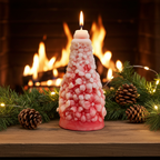 Vela artesanal decoración navidad encendida frente a una chimenea con guirnaldas y piñas.