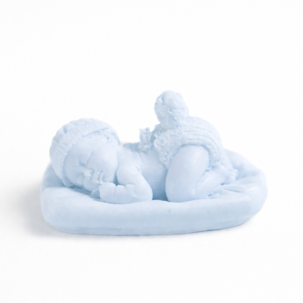 Vela artesanal en forma de bebé dormido en color azul pastel, elaborada en cera natural, detalle delicado ideal para recuerdo de bautizo o decoración infantil premium.