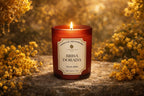 Vela aromática de lujo Brisa Dorada encendida entre flores doradas al atardecer, aroma marino y floral cálido inspirado en la luz del Mediterráneo.