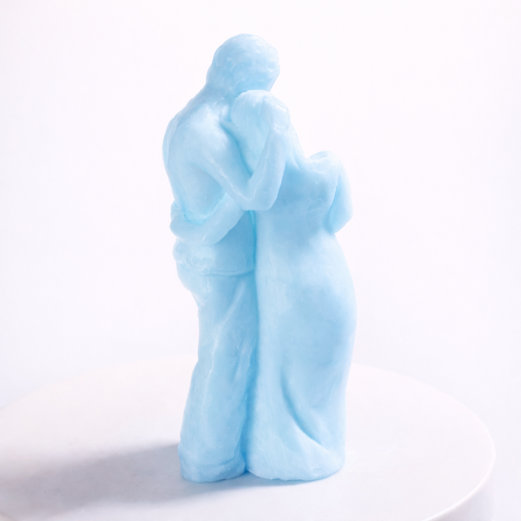 Vista posterior de vela escultórica de pareja abrazada en tono azul pastel, diseño emocional y moderno en cera ecológica, fotografía de estudio con iluminación suave y estética de lujo.