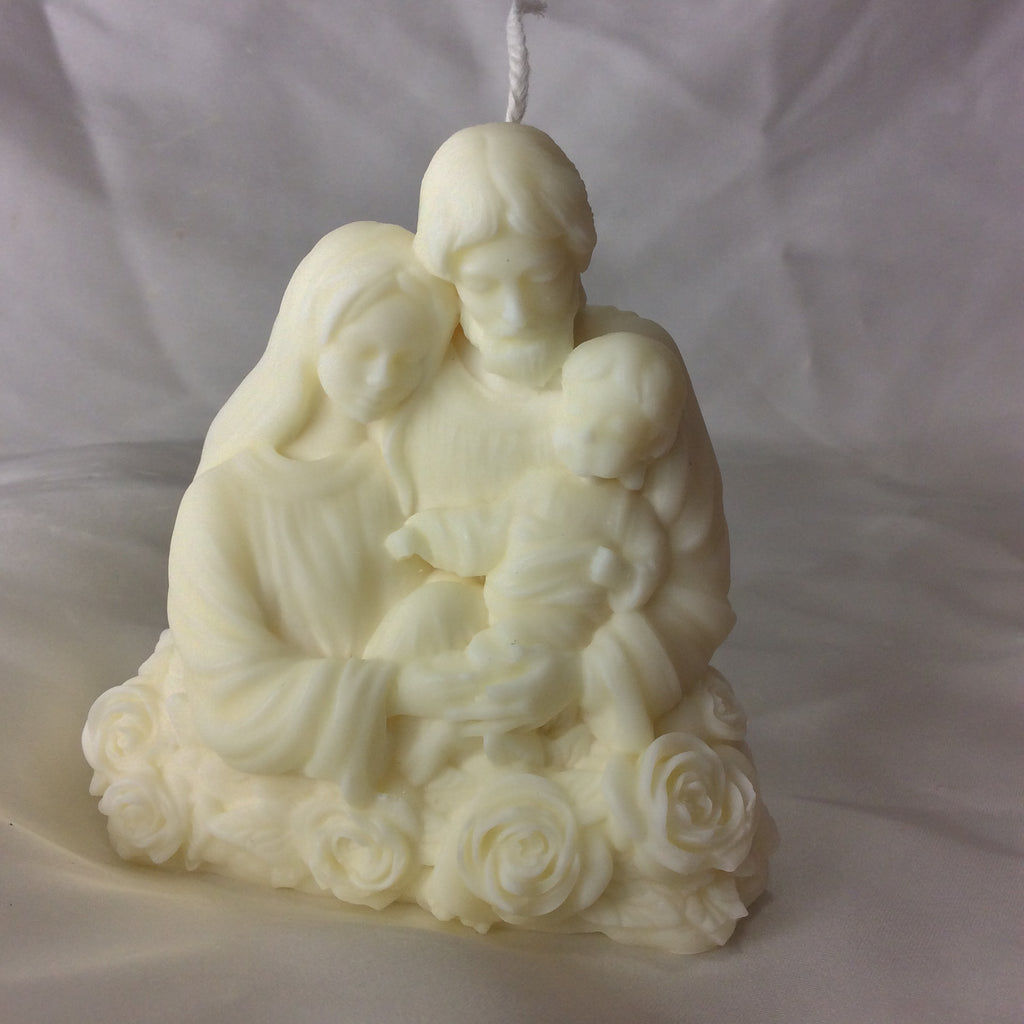 Vela artesanal de la Sagrada Familia con base de rosas sobre fondo blanco.