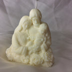 Vela artesanal de la Sagrada Familia con base de rosas sobre fondo blanco.
