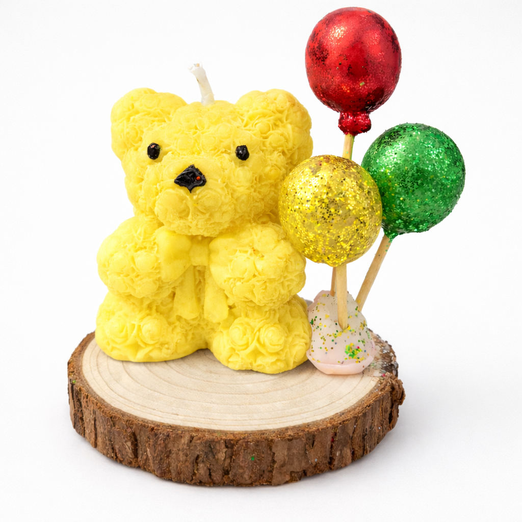 Vela decorativa artesanal en forma de osito amarillo con globos brillantes en rojo, verde y dorado, presentada sobre base de madera natural, fotografía de estudio con estética de lujo contemporáneo.