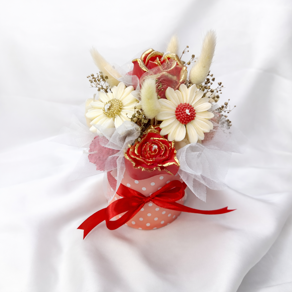 Detalle del Centro Latido con flores decorativas rojas y marfil, acabados dorados y textura artesanal, presentado en caja rosa con lazo rojo