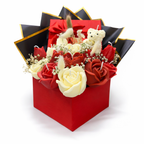 Centro Eternidad con flores artesanales en tonos rojos y marfil, presentado en caja roja de regalo con lazo satinado y envoltura negra con ribete dorado, símbolo de amor eterno y unión profunda.