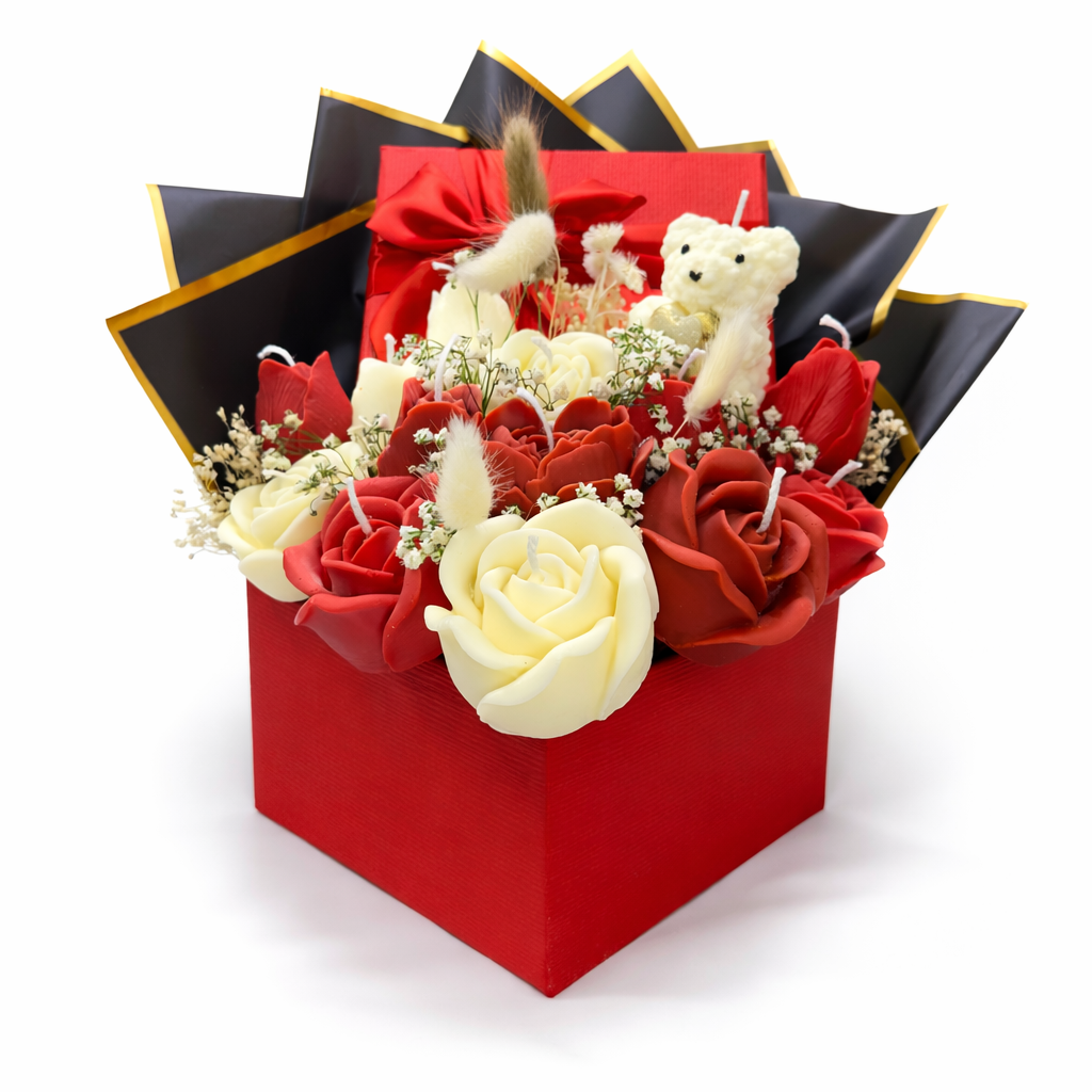 Centro Eternidad con flores artesanales en tonos rojos y marfil, presentado en caja roja de regalo con lazo satinado y envoltura negra con ribete dorado, símbolo de amor eterno y unión profunda.