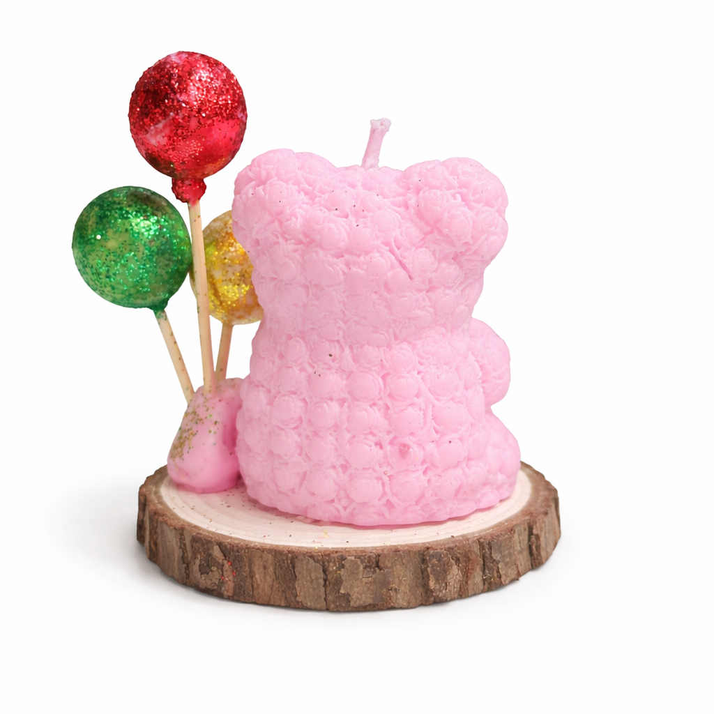 Vista posterior de vela artesanal en forma de osito rosa empolvado con globos decorativos brillantes, realizada en cera natural, fotografía minimalista de producto premium.