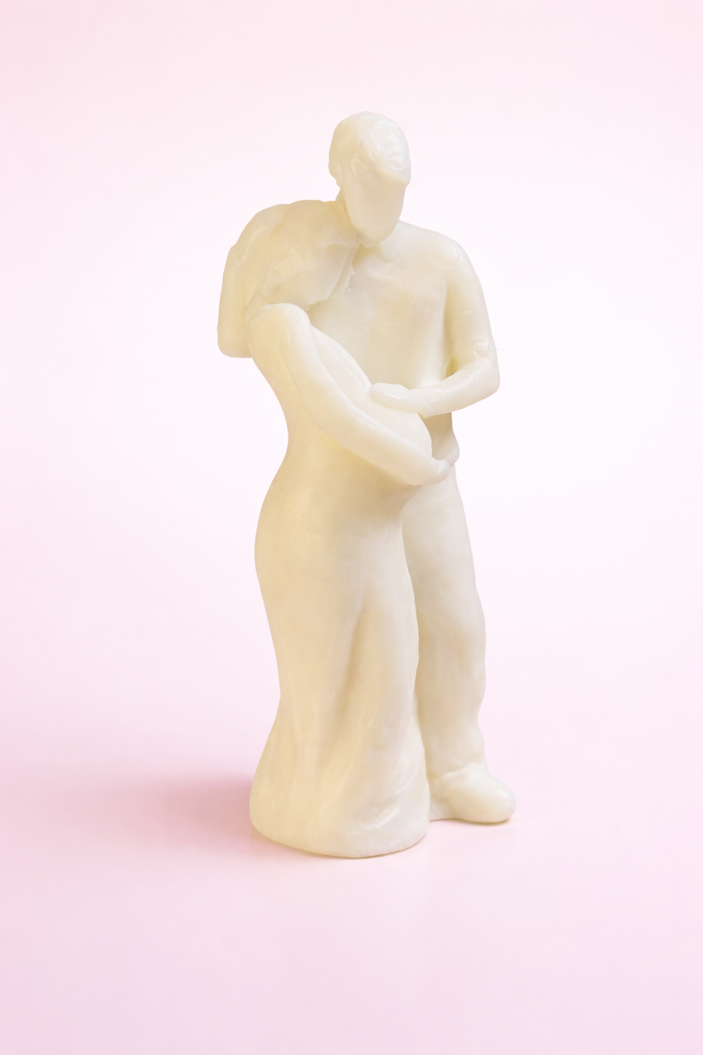Vela decorativa de diseño artístico representando una pareja en un abrazo íntimo, elaborada en cera vegetal ecológica, fotografía de estudio sobre fondo blanco con acabado editorial de alta gama.