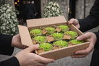 Caja con velas conmemorativas verdes preparadas como recuerdos para asistentes a funeral, presentación cuidada y elegante de obsequios de despedida.