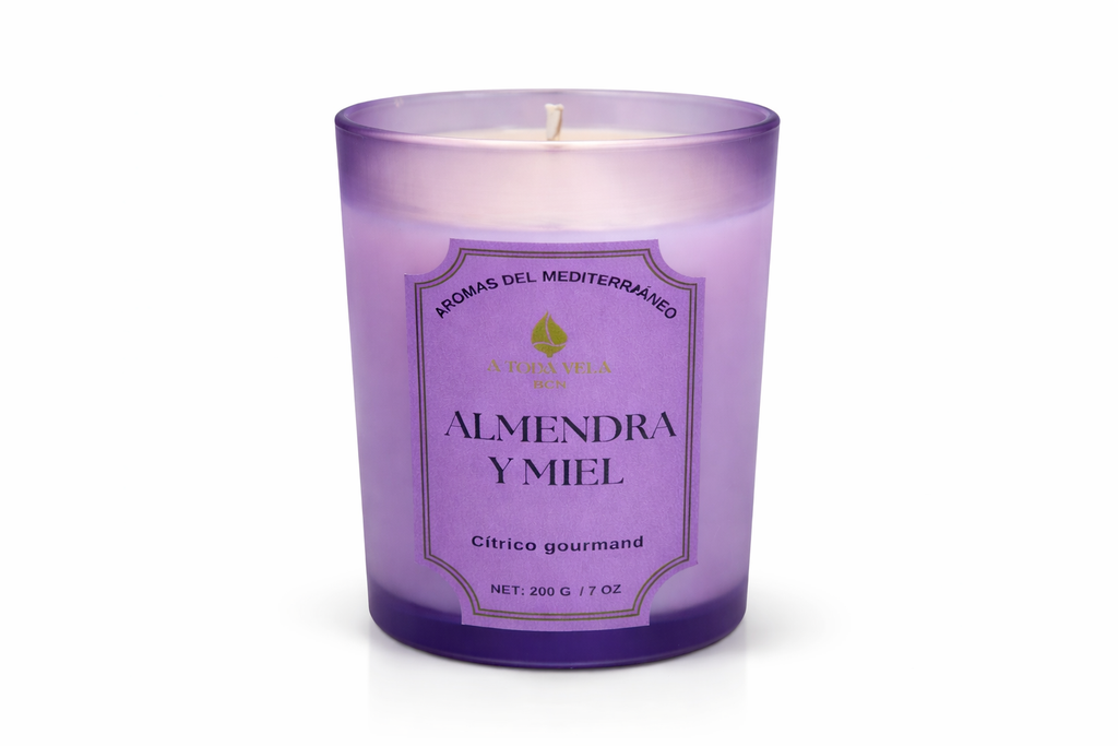 Vela aromática de lujo Almendra y Miel de la colección Aromas del Mediterráneo en vaso de cristal violeta, diseño elegante y sofisticado.