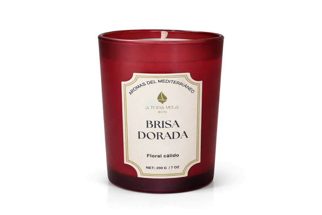 Vela aromática de lujo Brisa Dorada de la colección Aromas del Mediterráneo en vaso de cristal rojo, diseño elegante y aroma floral cálido.