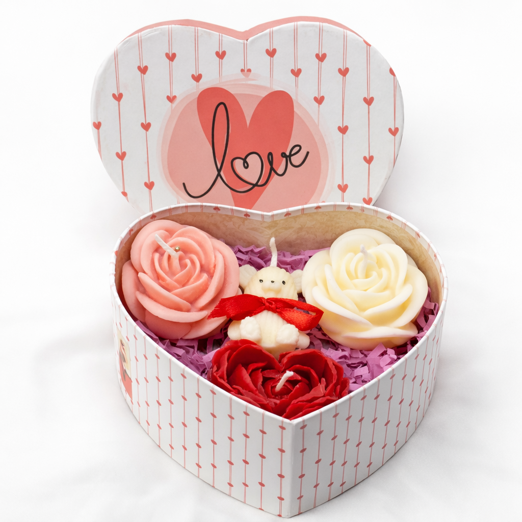 Vista superior de centro floral de cera en caja con forma de corazón, con flores de cera en tonos rosa, rojo y blanco, presentado como detalle romántico para pareja