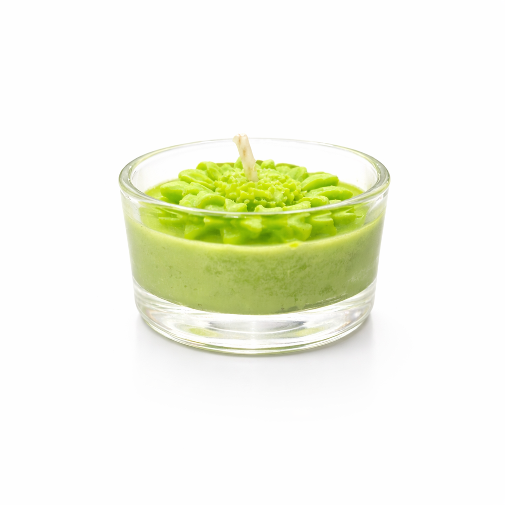 Vela conmemorativa artesanal verde en vaso de cristal, detalle floral en cera, recordatorio funerario elegante y minimalista sobre fondo blanco de estudio.
