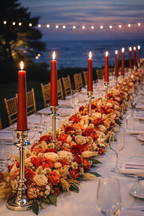 Velas cónicas Áurea de lujo en color carmesí sobre candelabros, dispuestas en una mesa de banquete nupcial al atardecer junto al mar, con arreglos florales elegantes y estética de boda exclusiva.