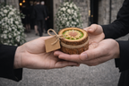 Entrega de recordatorio funerario elegante en forma de vela artesanal floral, gesto natural de homenaje a la entrada de ceremonia.