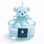 Vela infantil de diseño con osito de cera azul pastel en recipiente de cristal, acabado suave y elegante, fotografía de producto premium con estética editorial de revista de lujo.