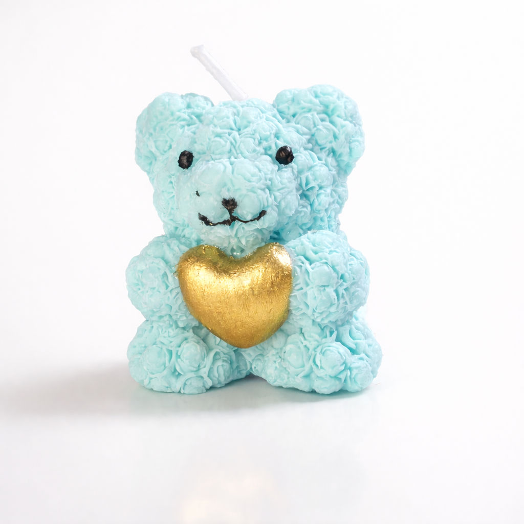 Vela decorativa artesanal en forma de osito azul pastel con corazón dorado, realizada en cera vegetal, fotografía de estudio minimalista con estética de lujo contemporáneo.