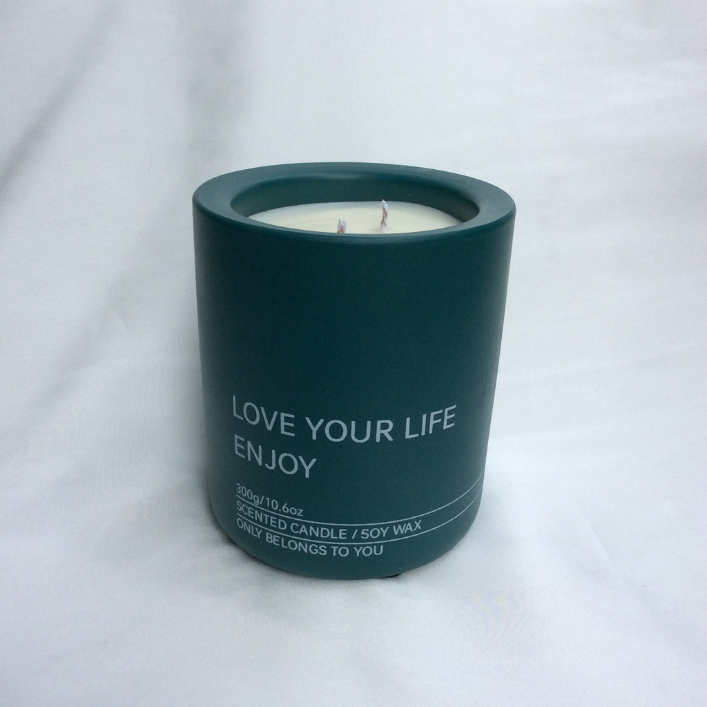 Vela perfumada Rumbo al Deseo Lujo verde oscuro de la colección "Una vela un rumbo". Contenedor con texto "LOVE YOUR LIFE ENJOY" y tres mechas.