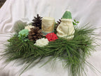 Vela de Papá Noel con gorro verde junto a una vela cilíndrica con relieve.
