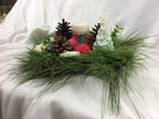 Vela con forma de calcetín de Navidad junto a un pino de cera y piñas.