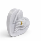 Vela escultórica corazón con manos unidas en tono gris perla, diseño contemporáneo en cera natural de alta calidad, detalle de anillo dorado integrado, pieza decorativa premium para interiores modernos y ambientes sofisticados.