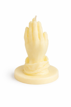 Vela escultórica en forma de manos rezando color amarillo vainilla, fabricada en cera natural, diseño artístico contemporáneo con base redonda, pieza decorativa sofisticada ideal para hogares elegantes y espacios wellness.