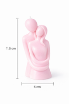 Vela escultórica romántica de 11.5 cm de alto y 6 cm de ancho en color rosa pastel, elaborada en cera natural, diseño moderno de pareja abrazada con líneas minimalistas, pieza decorativa exclusiva para regalo de boda o aniversario.