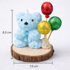 Vela decorativa artesanal en forma de osito azul con globos brillantes, dimensiones 8,5 cm de alto y 7,5 cm de ancho, presentada sobre base de madera, fotografía de estudio para e-commerce de lujo