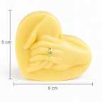 Vela escultórica corazón con manos unidas de 5 cm de alto y 6 cm de ancho, elaborada en cera natural color amarillo suave, diseño minimalista con detalle dorado, pieza decorativa compacta y exclusiva para regalo premium.