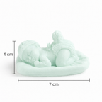 Vela artesanal bebé dormido en color verde suave, dimensiones 4 cm de alto y 7 cm de ancho, recuerdo de bautizo compacto en cera natural.