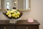 Vela decorativa ángel bebé rosa pastel sobre mueble elegante junto a ramo floral, decoración sofisticada para bautizo o habitación infantil de lujo.