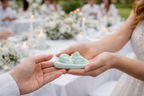 Entrega de vela artesanal bebé dormido verde pastel durante celebración elegante al aire libre, detalle exclusivo para bautizo o evento especial.