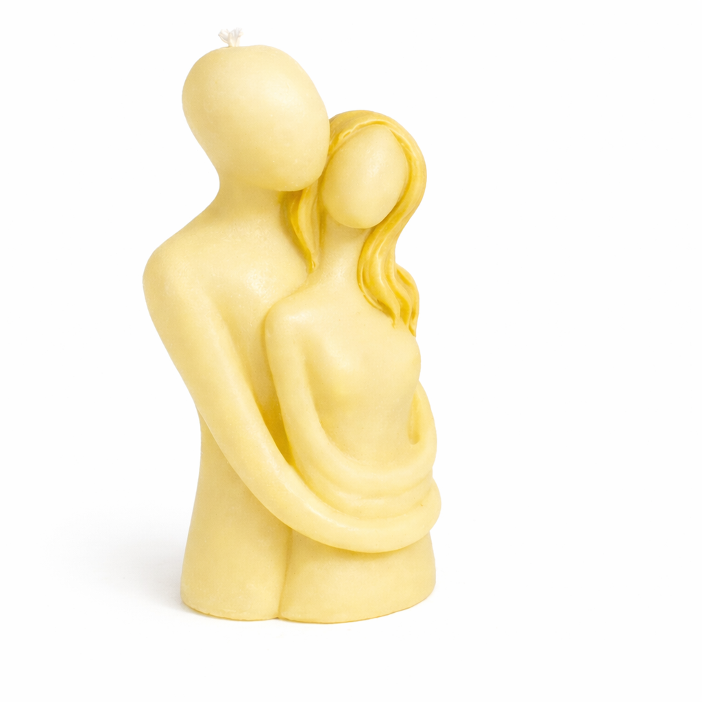 Vela artística color amarillo crema con figura estilizada de pareja abrazada, fabricada en cera natural premium, diseño escultórico elegante de inspiración contemporánea, objeto decorativo sofisticado para hogar o regalo romántico.