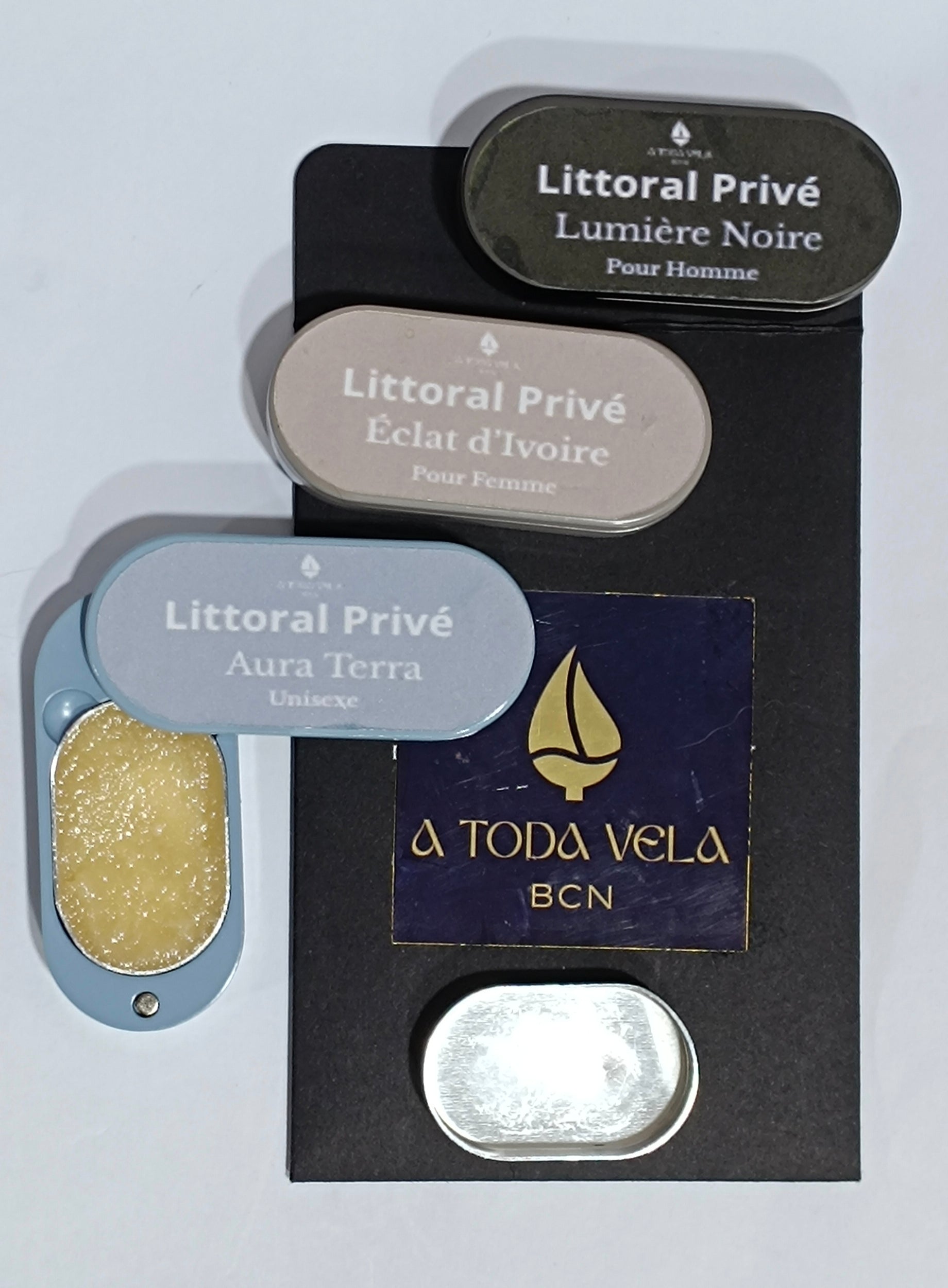 Estuches apilados de la colección Litoral Privé (Éclat d'Ivoire, Lumière Noire, Aura Terra) junto a un recambio metálico vacío, mostrando el sistema recargabl