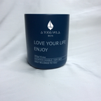 Primer plano de la vela ecológica A Toda Vela BCN Rumbo al Horizonte en tarro azul marino. Se distinguen el logo y el texto "SCENTED CANDLE / SOY WAX 300g". La vela de cera vegetal 100% ecológica y mecha de algodón representa la fragancia fresca, mineral y profunda inspirada en el mar, con notas de Ámbar Solar y Cedro.