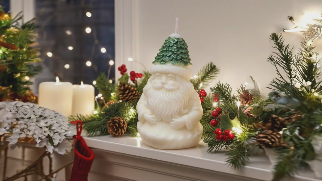 Vela Papá Noel Gorro Árbol, figura tallada de Santa Claus con gorro de pino verde y barba blanca, sobre repisa navideña con luces y guirnaldas.